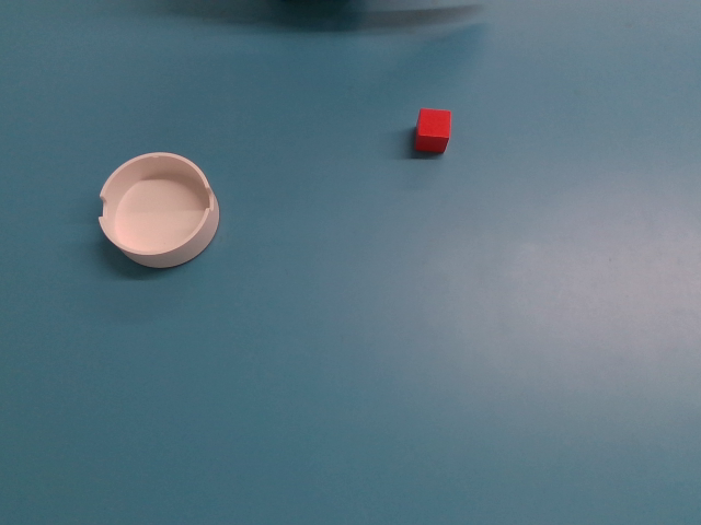 Picking the green cube from the white area, and placing it within the red area